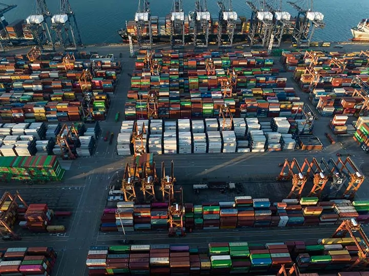 Stacks of shipping containers at a U.S. port, including Chinese carriers COSCO and China Shipping.